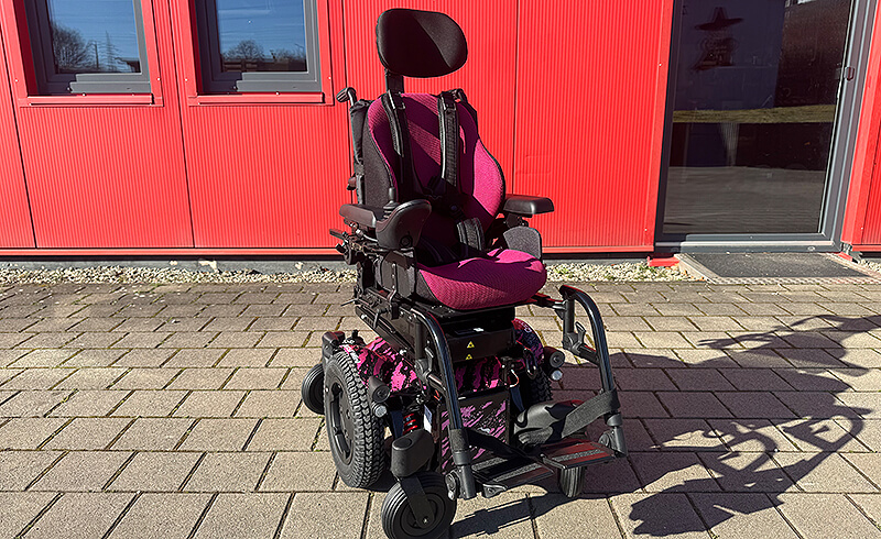 Elektrischer Kinderrollstuhl mit individuell angepasstem Sitzsystem vor einem Gebäude