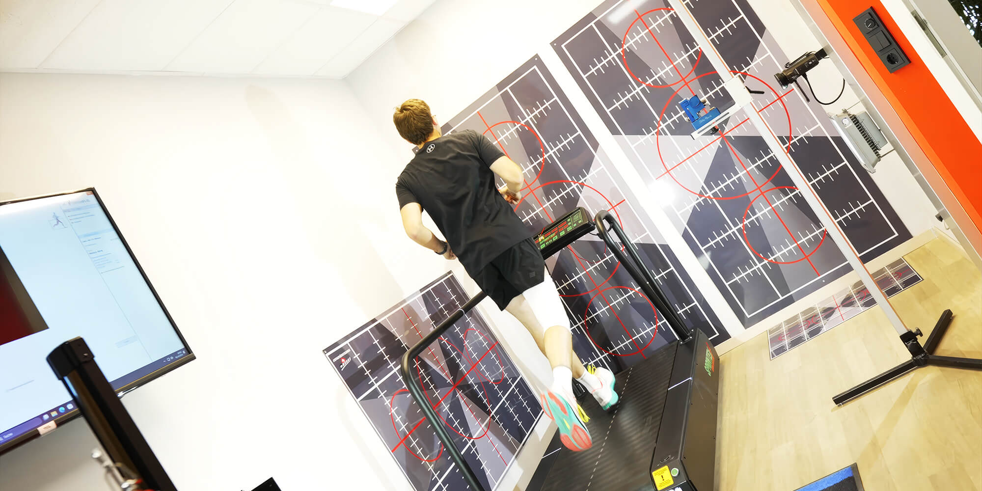 Rückansicht einer Laufanalyse auf dem Laufband. Analyse der Fersenstellung und Beinführung mithilfe markierter Messflächen und visueller Referenzsysteme.